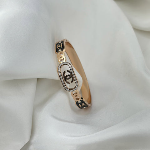 Gold bracelet with Chanel logo on a white fabric background