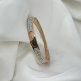 Gold bracelet with diamond accents on a white fabric background