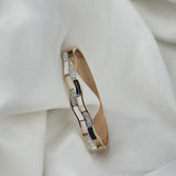 Gold bracelet with diamond accents on a white fabric background