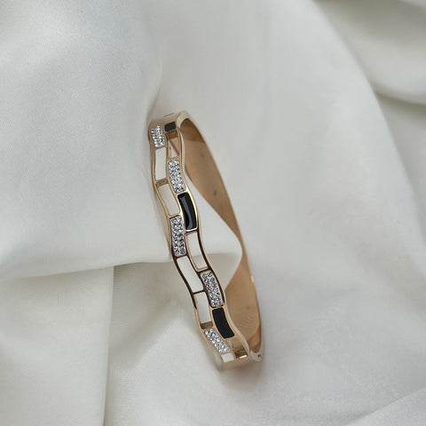 Gold bracelet with diamond accents on a white fabric background