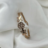 Gold bracelet with floral design on a white fabric background