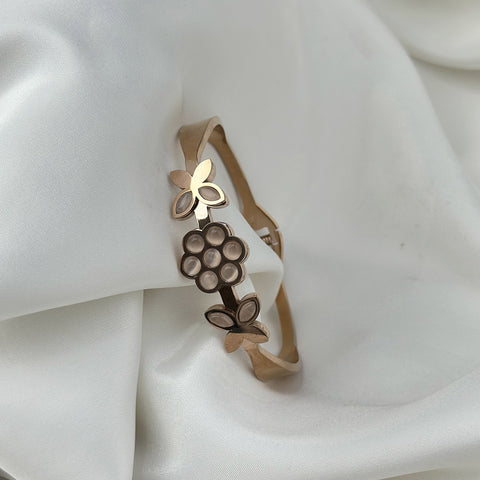 Gold bracelet with floral design on a white fabric background