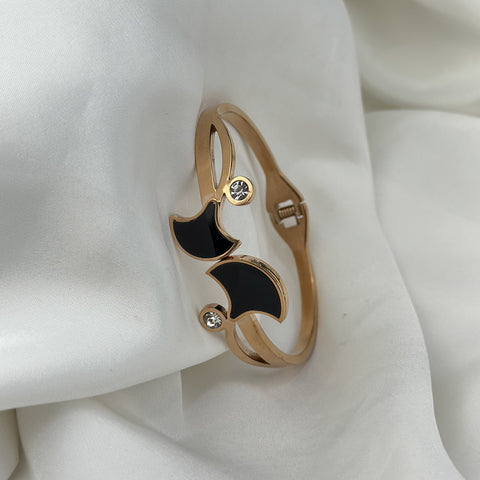 Gold bracelet with black accents on a white fabric background