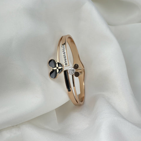 Gold bracelet with black and white elements on a white fabric background