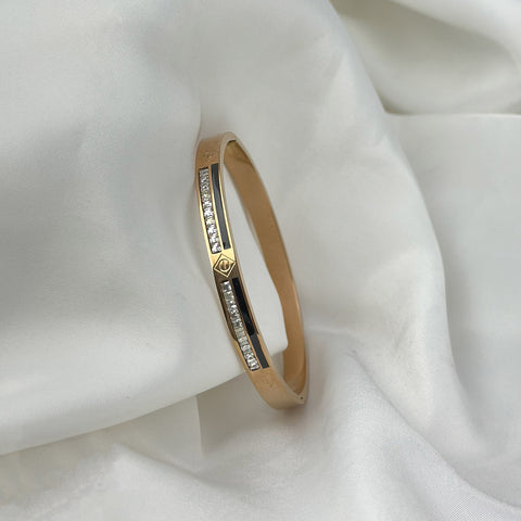 Gold bracelet with embedded diamonds on a white fabric background