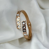 Rose gold bracelet with gemstones on a white fabric background