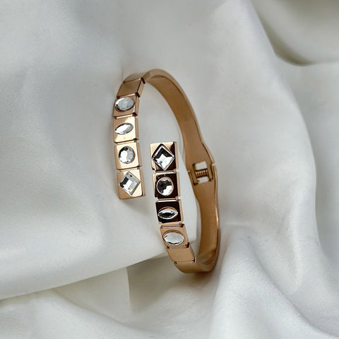 Rose gold bracelet with gemstones on a white fabric background