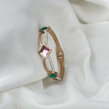 Gold bracelet with gemstones on a white fabric background