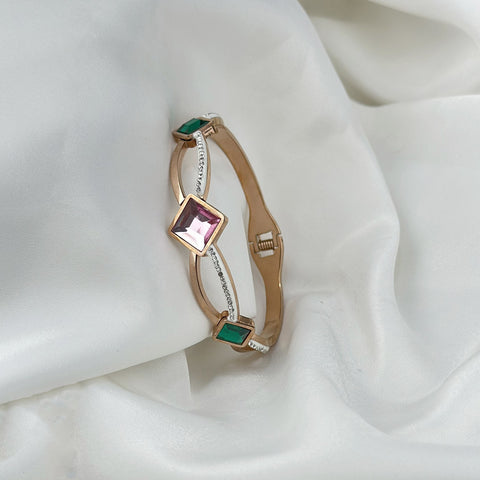 Gold bracelet with gemstones on a white fabric background