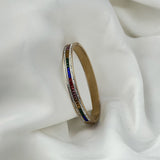 Gold bracelet with colorful stones on a white fabric background
