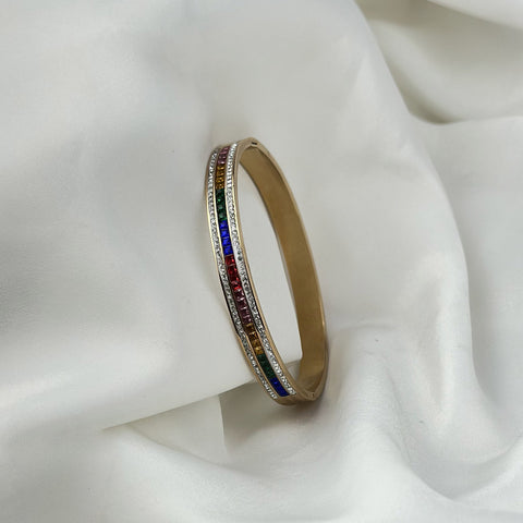 Gold bracelet with colorful stones on a white fabric background