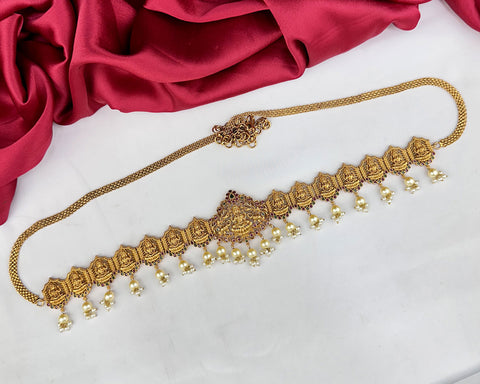 Gold necklace with decorative elements on a white surface with red fabric