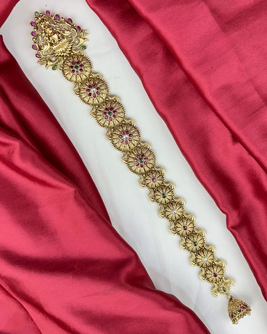 Decorative gold belt with gemstones on a red and white fabric background