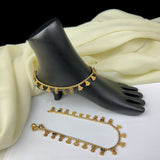 Gold anklets on a black mannequin foot with a white fabric background