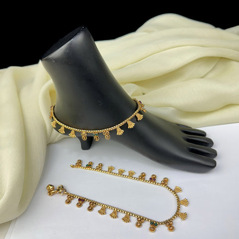 Gold anklets on a black mannequin foot with a white fabric background