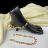 Gold anklets on a black mannequin foot with white fabric background