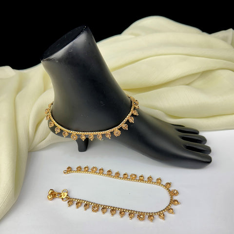 Gold anklets on a black mannequin foot with white fabric background