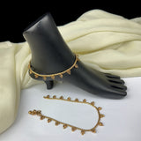 Gold anklets on a black foot mannequin and white fabric background