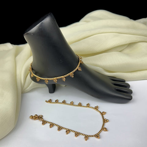 Gold anklets on a black foot mannequin and white fabric background