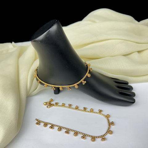 Gold anklets on a black mannequin foot with a white fabric background
