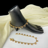 Gold anklets on a black shoe mannequin with a white fabric background