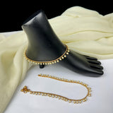 Gold necklace with pearl-like beads on a black mannequin hand and white fabric background