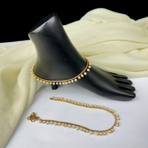 Gold necklace with pearl-like beads on a black mannequin hand and white fabric background