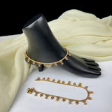 Gold anklets on a black mannequin foot with a white fabric background