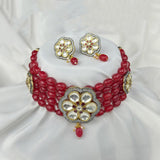 Red beaded necklace with floral designs on a white fabric background