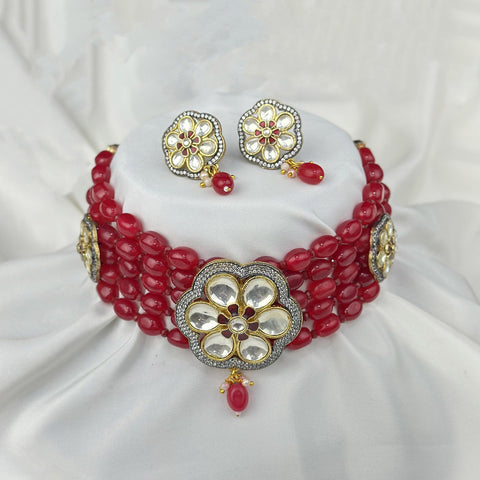 Red beaded necklace with floral designs on a white fabric background