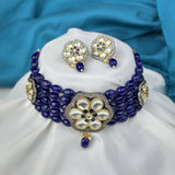 Jewelry set with a blue beaded necklace and matching earrings on a white cushion with a blue fabric background.