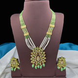 Green and gold necklace with matching earrings on a brown stand.