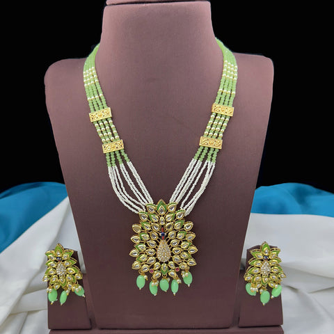 Green and gold necklace with matching earrings on a brown stand.