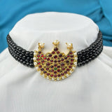 Decorative necklace with black beads and a gold heart-shaped pendant on a white cushion.