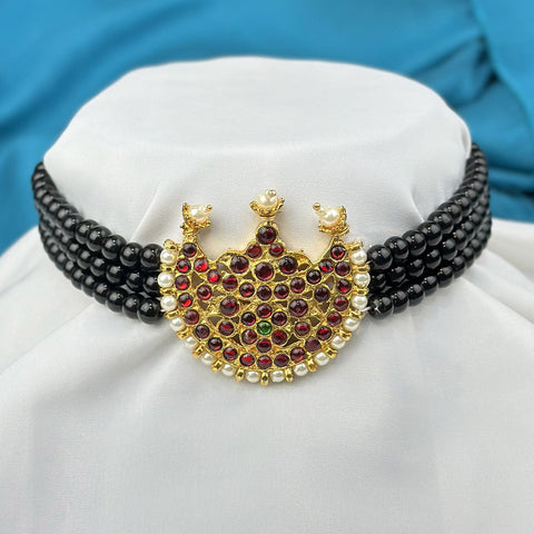 Decorative necklace with black beads and a gold heart-shaped pendant on a white cushion.