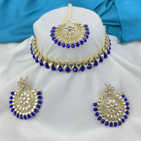 Jewelry set with blue stones and gold accents on a white and blue fabric background