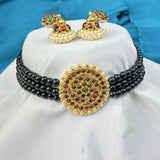 Black beaded necklace with gold and multicolor pendant on a white cushion, blue background