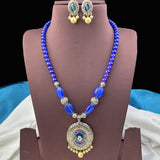 Blue beaded necklace with a pendant and matching earrings on a brown stand.