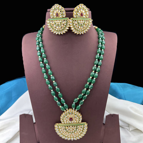 Green beaded necklace with gold pendants and matching earrings on a mannequin.