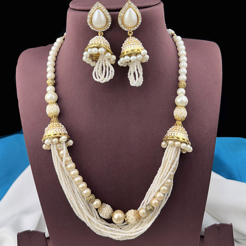 Pearl necklace and earrings set on a mannequin bust with a colorful background