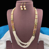 Pearl necklace and earrings set on a purple stand with a black background