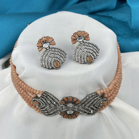 Jewelry set with earrings and a necklace on a white cushion with a blue fabric background