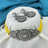 Jewelry set with a yellow choker and matching earrings on a white cushion with blue fabric background