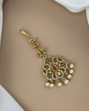 Decorative hairpin with gold, pearls, and gemstones on a neutral background