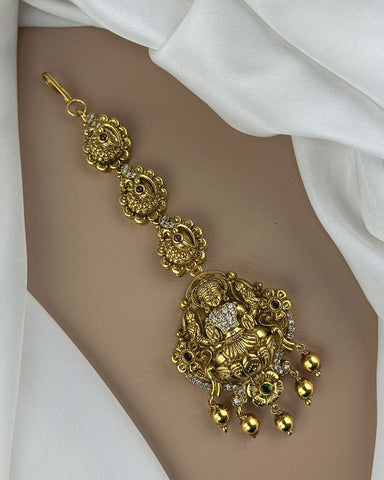 Gold bracelet with intricate designs on a white fabric background