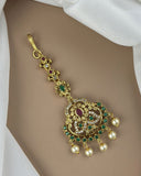 Gold pendant with pearls and gemstones on a white fabric background