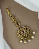 Decorative keychain with gold design, pearls, and gemstones on a neutral background