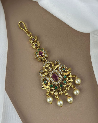Gold pendant with gemstones and pearls on a beige background