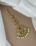 Gold necklace with pearls and gemstones on a white fabric background