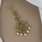 Decorative gold pendant with pearls and gemstones on a beige background